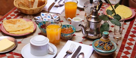 Et morgenbord med forskellige morgenmadsprodukter, blandt andet brød, æg, juice og en tekedel.