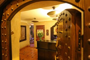 Un espace d’accueil avec un comptoir de réception en bois, une horloge et un mur décoré d’un motif.