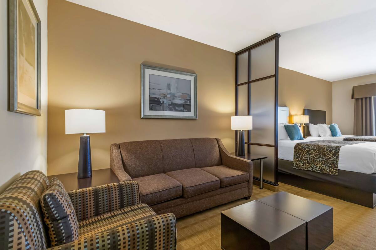 Una habitación de hotel con sofá, cama, mesa de centro y dos lámparas.