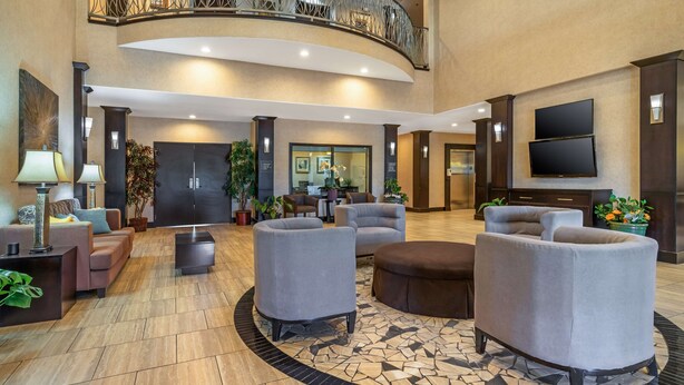 A spacious lobby with a curved balcony, multiple seating areas, and a large flat-screen TV. - Best Western Plus Lytle Inn & Suites (Lytle)