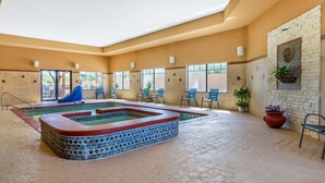 An indoor swimming pool with a tiled design, surrounded by chairs and potted plants. - Best Western Plus Lytle Inn & Suites (Lytle)