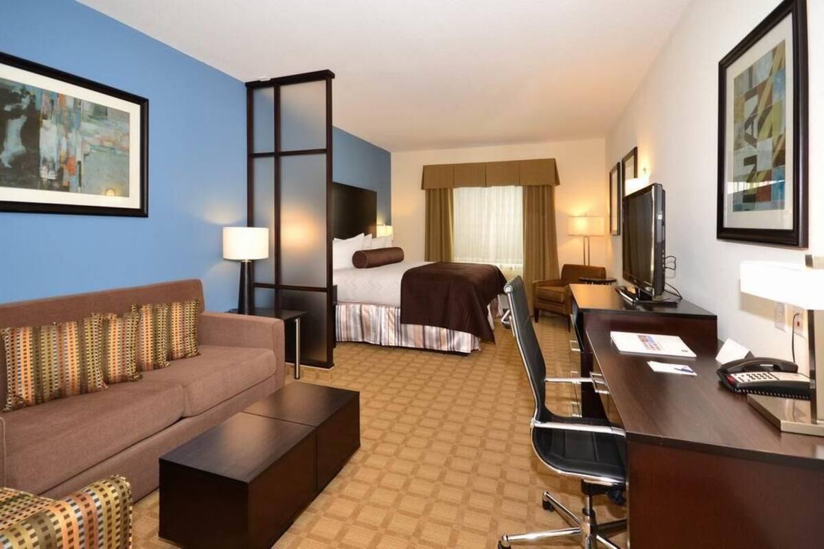 Habitación de hotel con sofá, cama, escritorio y televisor.