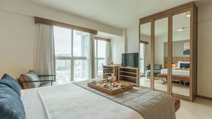 A hotel room with a large bed, a TV, a desk with a chair, a wardrobe, and a window with curtains. - Saint Moritz Hplus Express (Brasília)