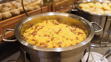 Buffet com uma grande panela de arroz amarelo, decorado com bacon.