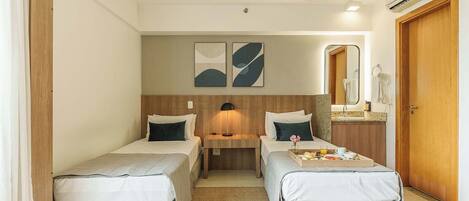 Una habitación de hotel con dos camas individuales, una mesita con desayuno, un espejo y un equipo de aire acondicionado.