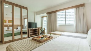 A hotel room with a large bed, a TV, a desk with a chair, a dining table with breakfast, and a window with curtains. - Saint Moritz Hplus Express (Brasília)