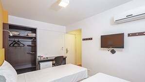 A hotel room with a bed, a desk, a wardrobe, and an air conditioning unit. - Camboriú Express (Balneário Camboriú)