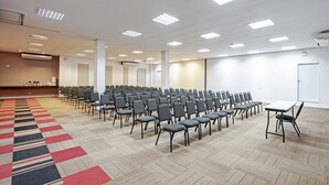 A conference room with rows of chairs, a carpeted floor, and ceiling lights. - Camboriú Express (Balneário Camboriú)