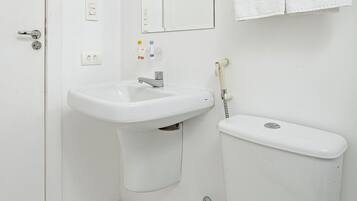 Un baño blanco con lavamanos, espejo, inodoro y toallero.
