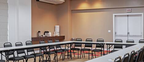 Un salón de conferencias con una larga mesa, sillas, un atril y una puerta con la inscripción 'SAIDA'.