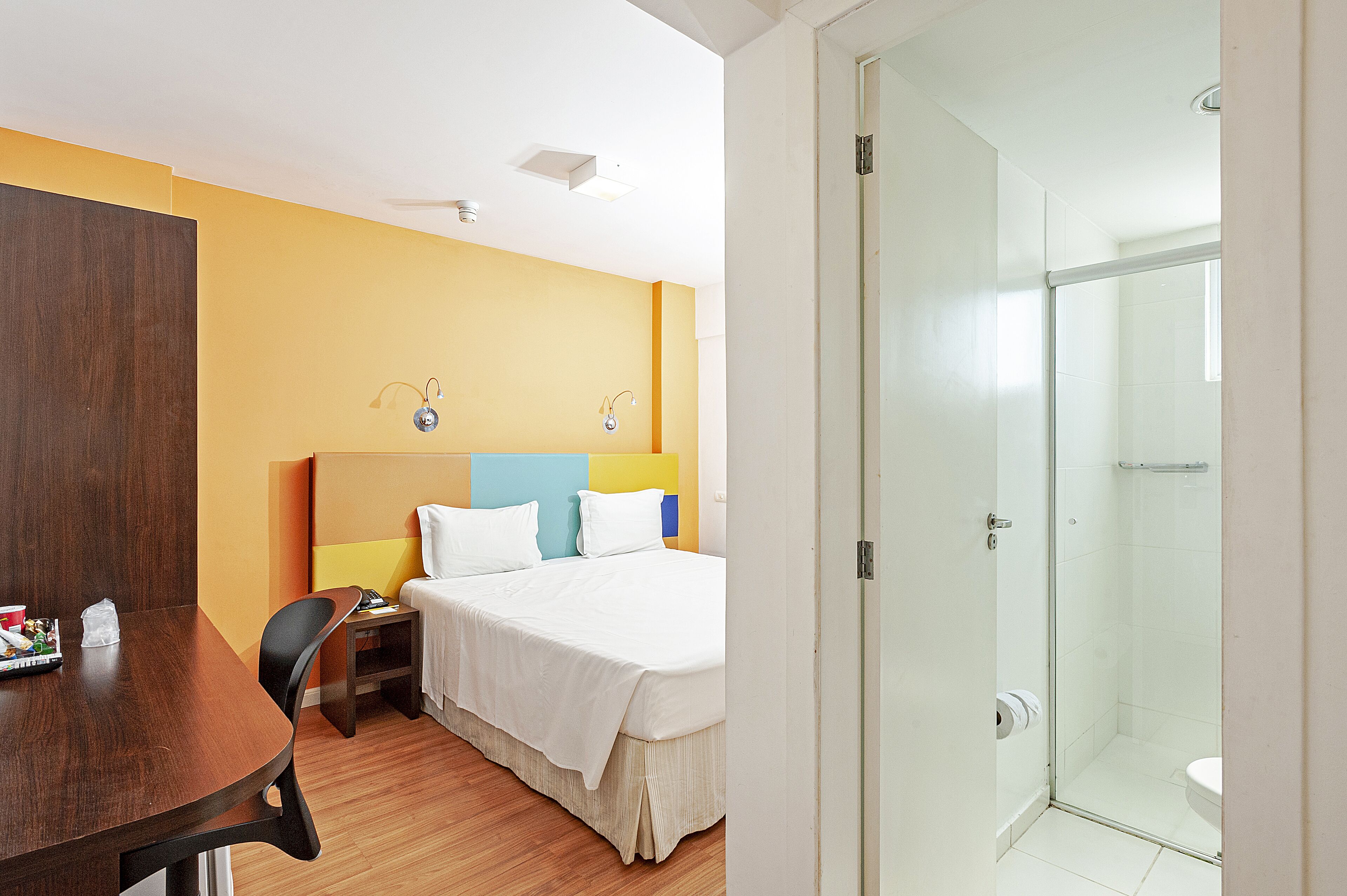 Ein Hotelzimmer mit Bett, Nachttisch und Duschbereich.