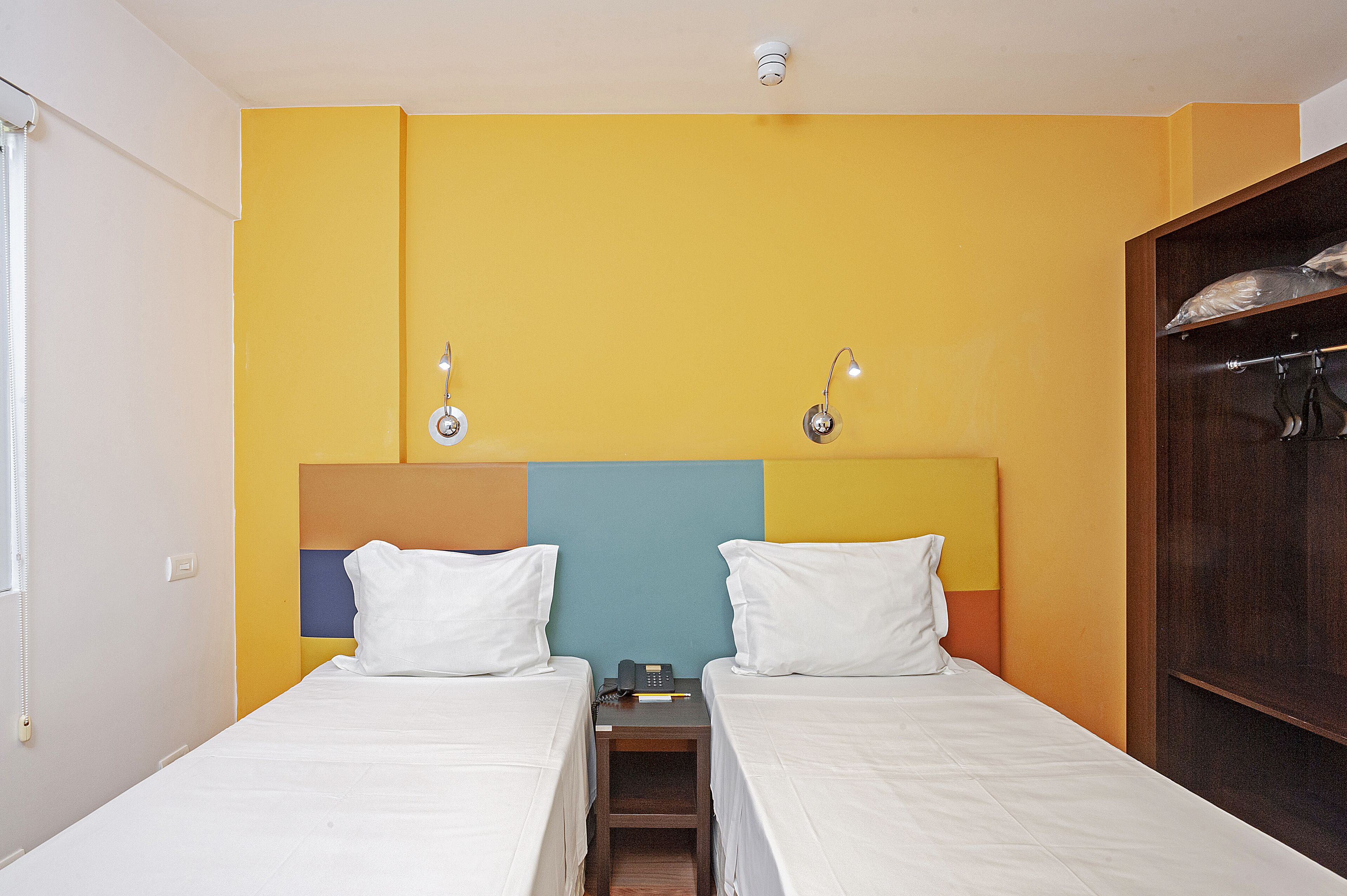 Habitación de hotel con dos camas, una mesita de noche y un armario.