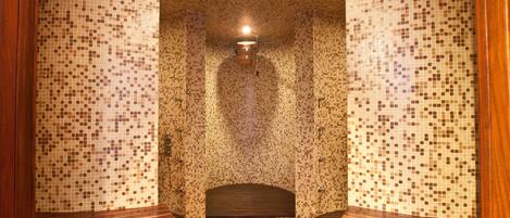 Una habitación con paredes de mosaicos, un banco de madera y una lámpara central.