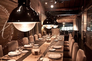 Enjoy a sophisticated dining experience at this elegant space, featuring a long table set with fine china and crystal glassware.
