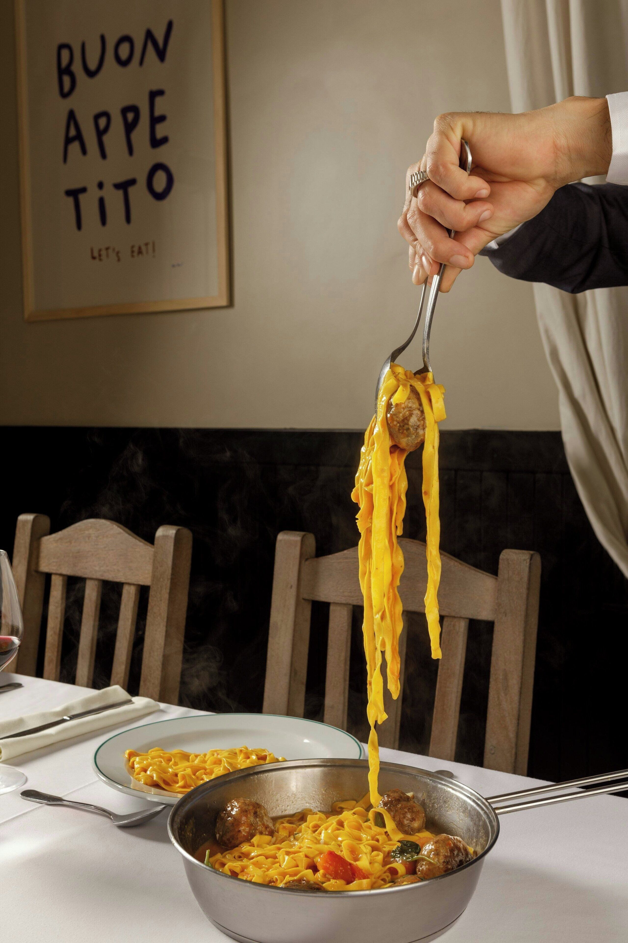 Un tavolo da pranzo con una ciotola di pasta e un cucchiaio.