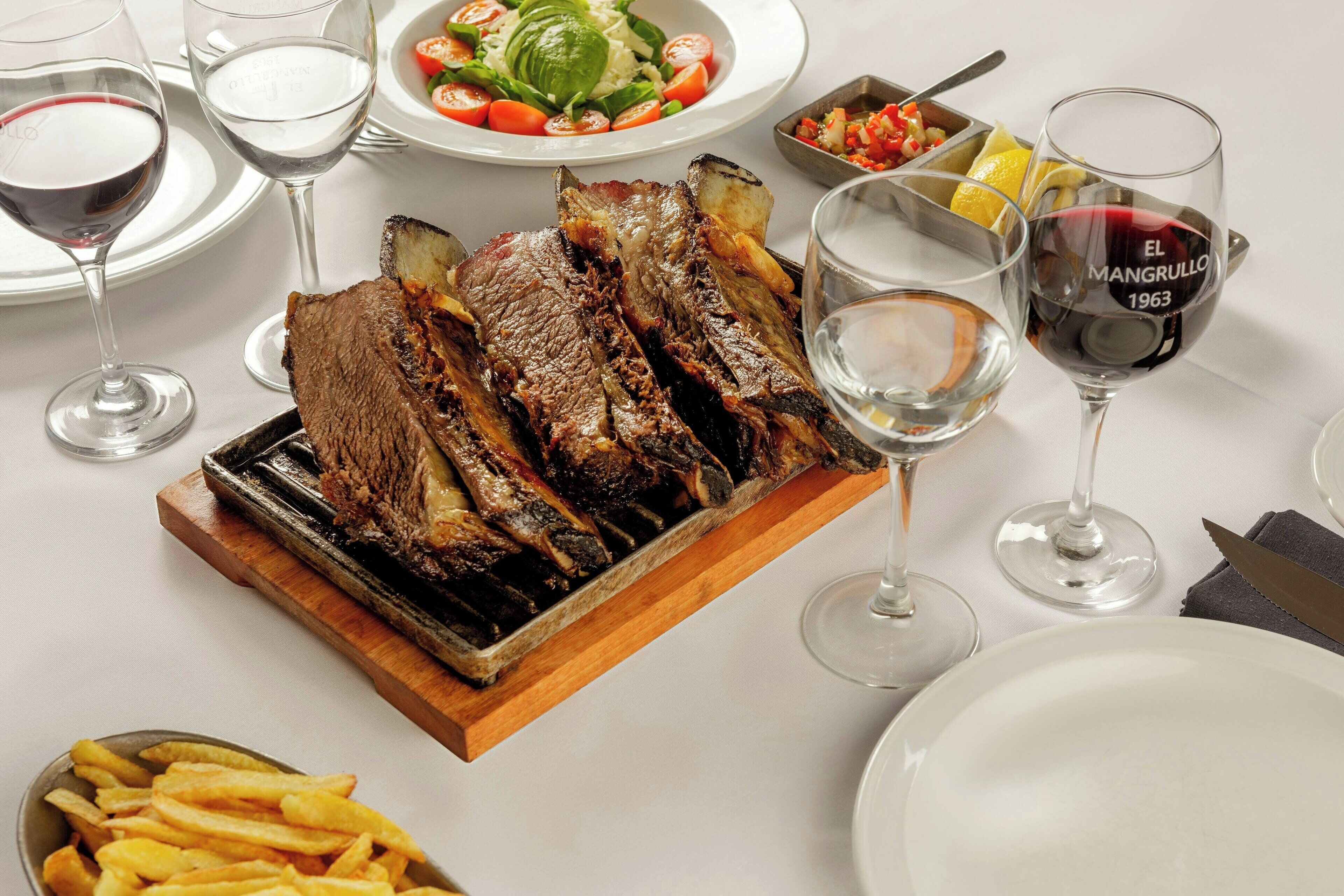 A dining table set with plates, glasses, and a roasted meat dish.