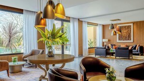 Un vestíbul d'hotel modern amb seients de cuir, una taula rodona i il·luminació penjant.
