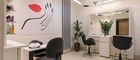 A modern salon with black chairs, a large mirror, and a wall art piece.