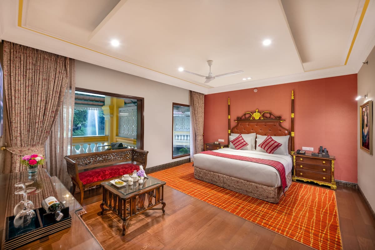 A spacious bedroom with a large bed, a wooden nightstand, a bedside table, and a view of a balcony.