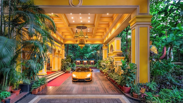 A luxurious hotel entrance with a red carpet, potted plants, and a car parked in the center. - Mayfair Lagoon (Bhubaneshwar)