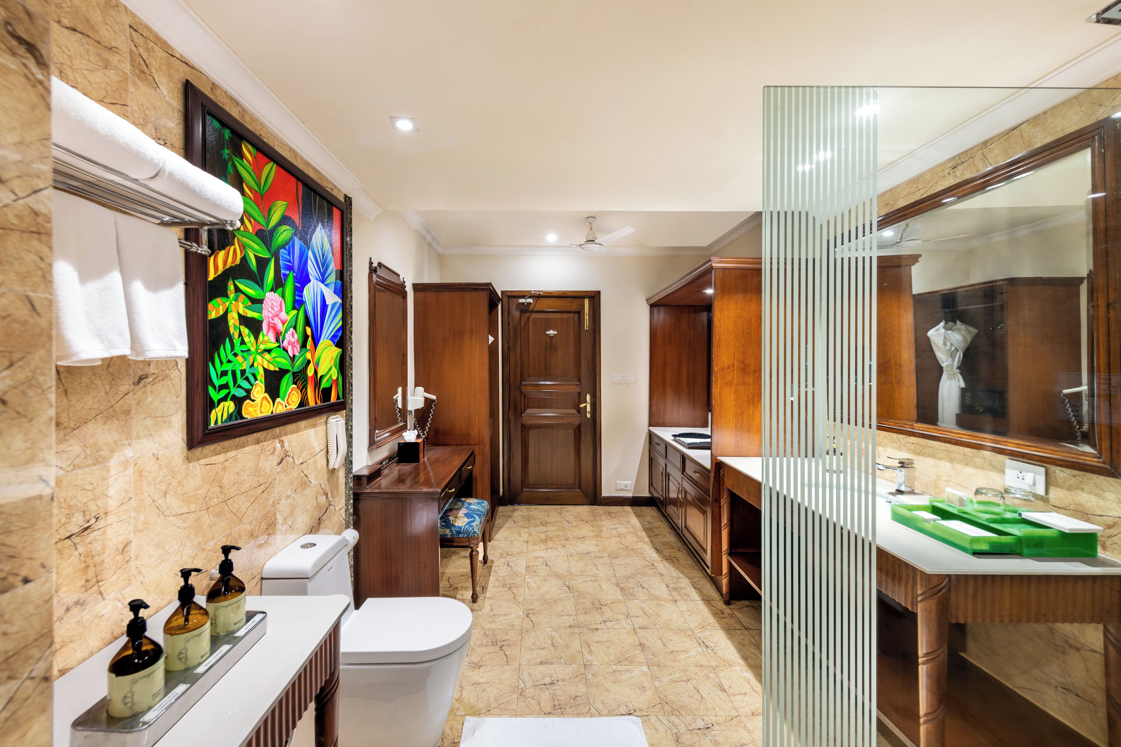 A modern bathroom with a marble floor, a large mirror, a toilet, a sink, and a shower area.