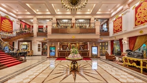 A grand lobby with a central floral arrangement, a staircase, and a reception desk. - Mayfair Lagoon (Bhubaneshwar)