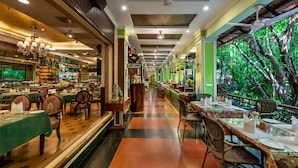A restaurant with a long counter, chairs, and tables set for dining. - Mayfair Lagoon (Bhubaneshwar)