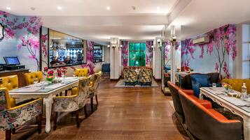 A dining area with a long table, chairs, and a bar in the background.