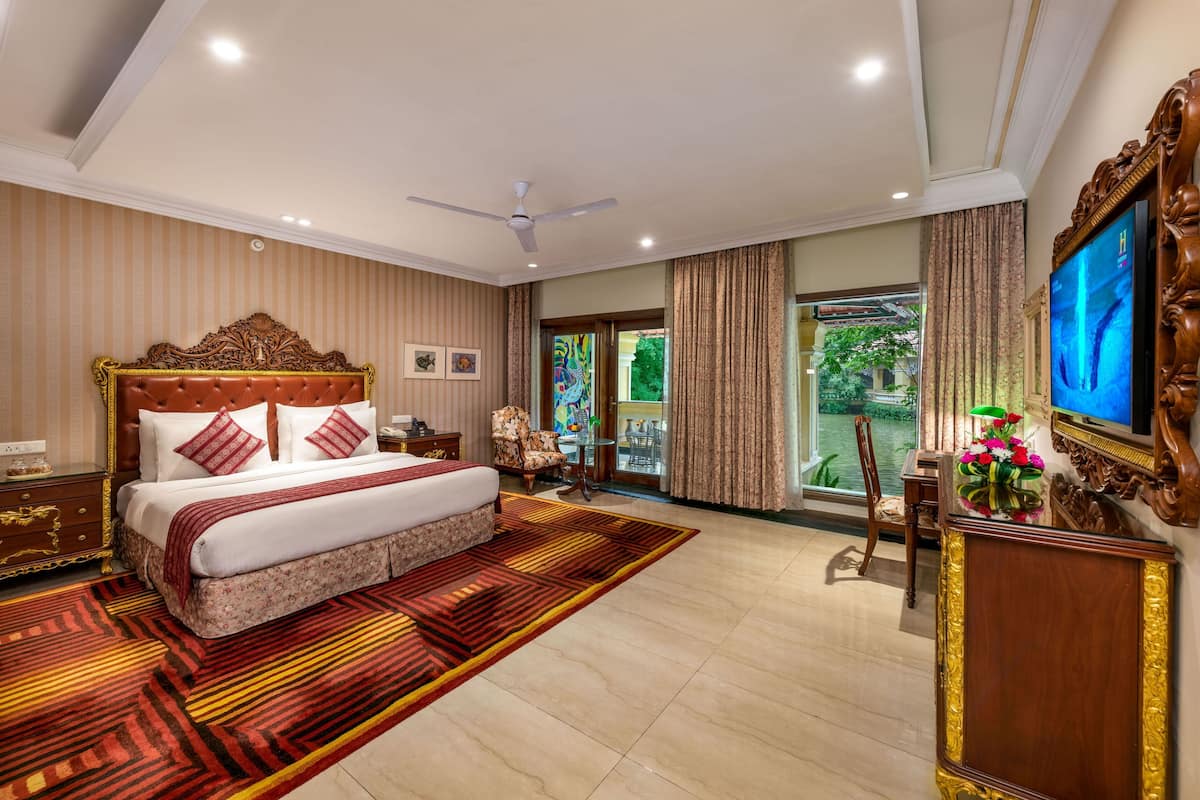 A spacious bedroom with a large bed, a ceiling fan, and a television.