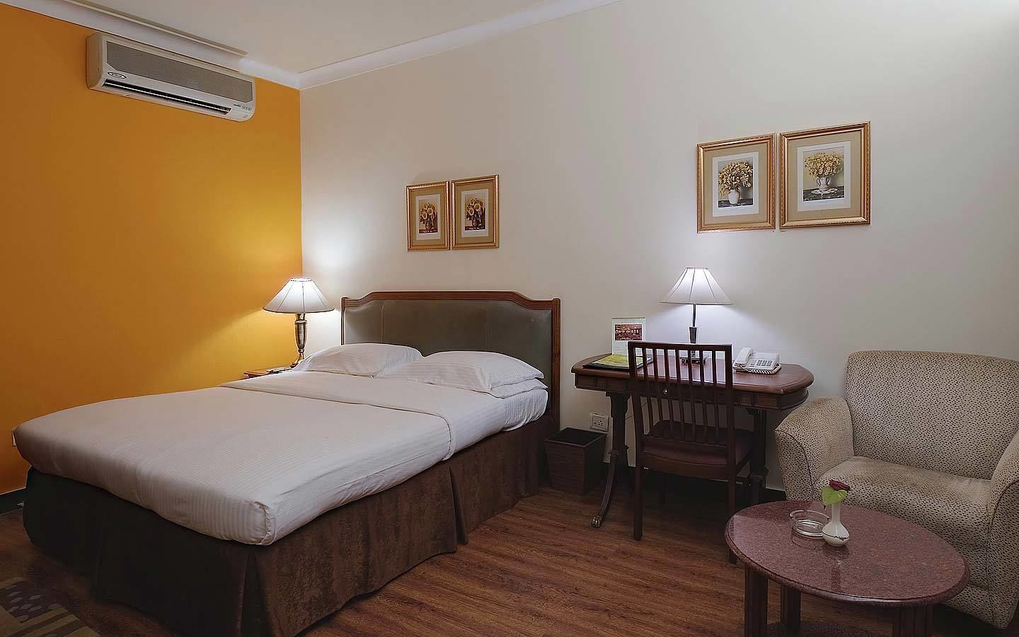 Una habitación de hotel con una cama, un escritorio, una silla y dos lámparas.