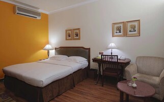 Una habitación de hotel con una cama, un escritorio, una silla y dos lámparas.