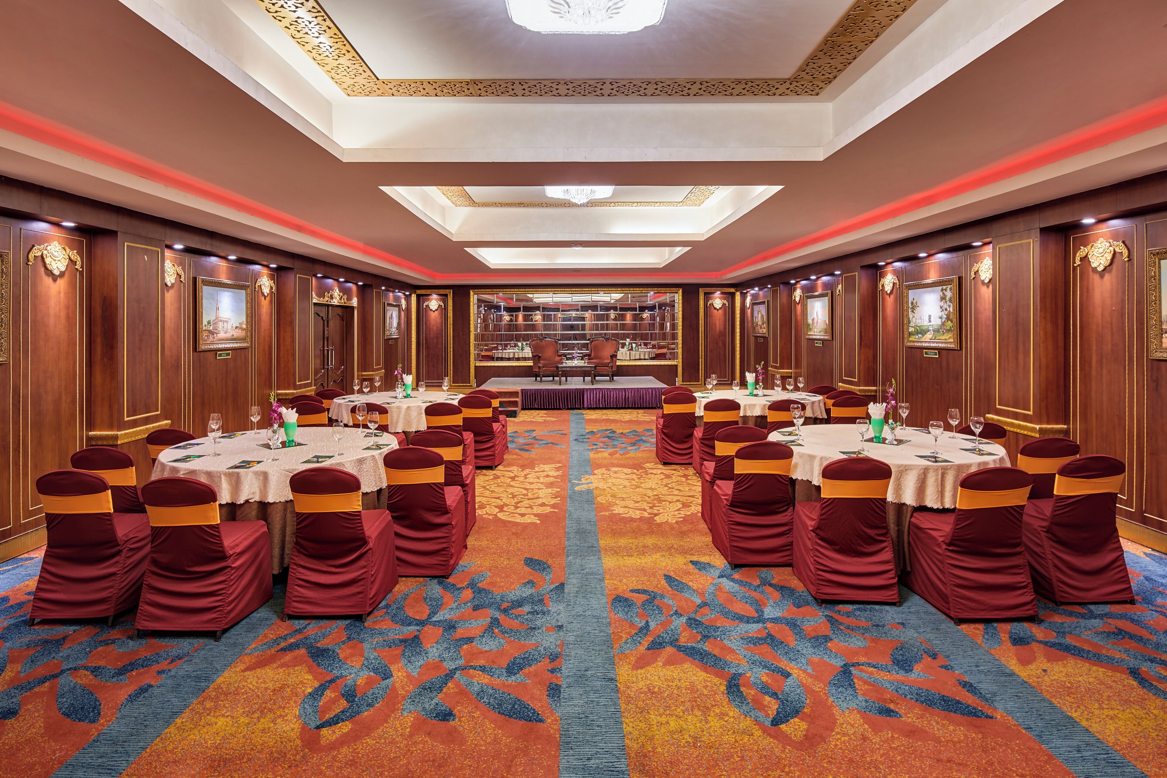 A conference room with round tables, red chairs, and a patterned carpet.