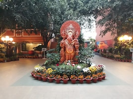 Una gran estatua de una deidad rodeada de plantas y flores en macetas.