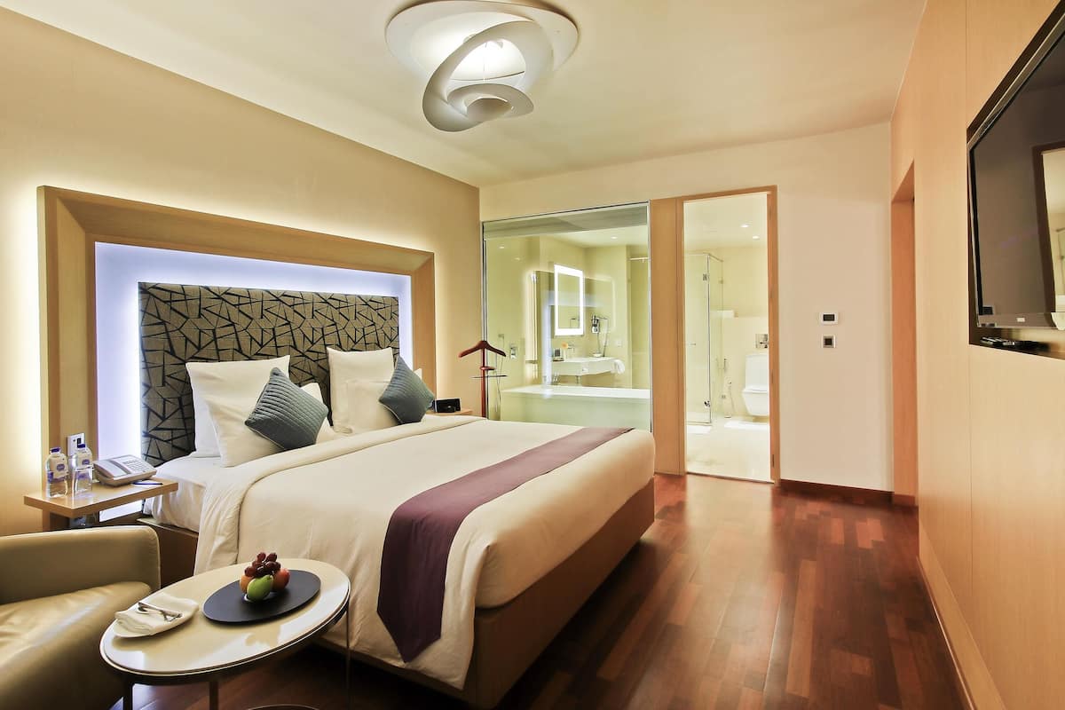 Een hotelkamer met een bed, nachtkastje, stoel en televisie.