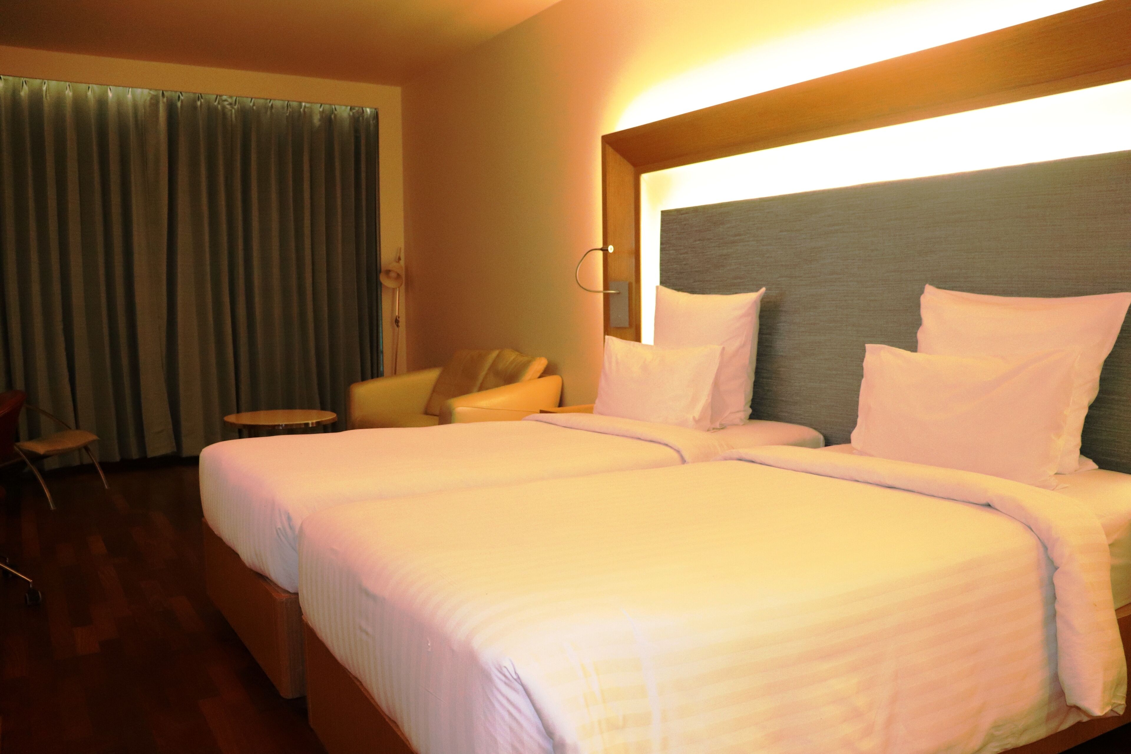 Une chambre d’hôtel avec un grand lit, une petite table, une chaise et un rideau.