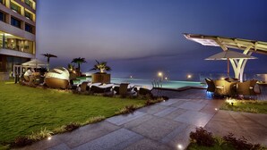 A well-lit outdoor lounge area with seating and a view of the ocean at dusk. - Novotel Visakhapatnam Varun Beach Hotel (Visakhapatnam)