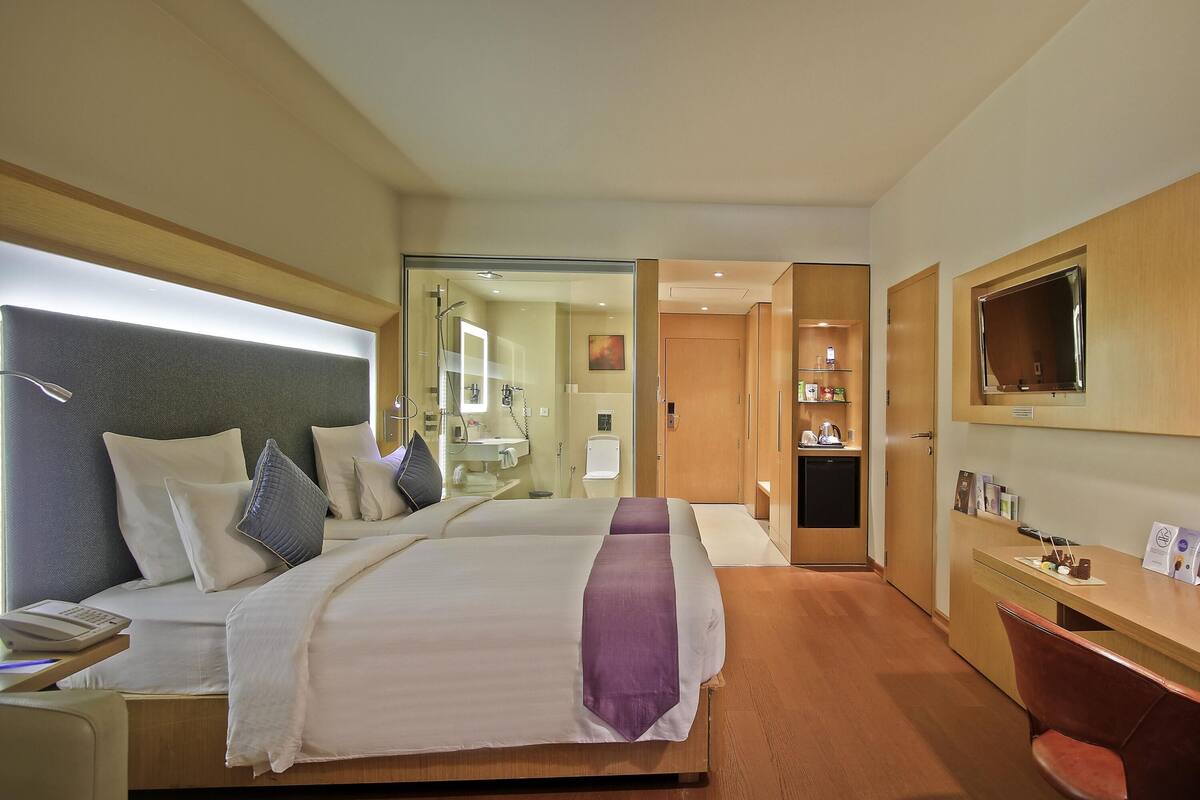 Une chambre d’hôtel comprenant un lit, une table de chevet, une lampe et un bureau avec une chaise.