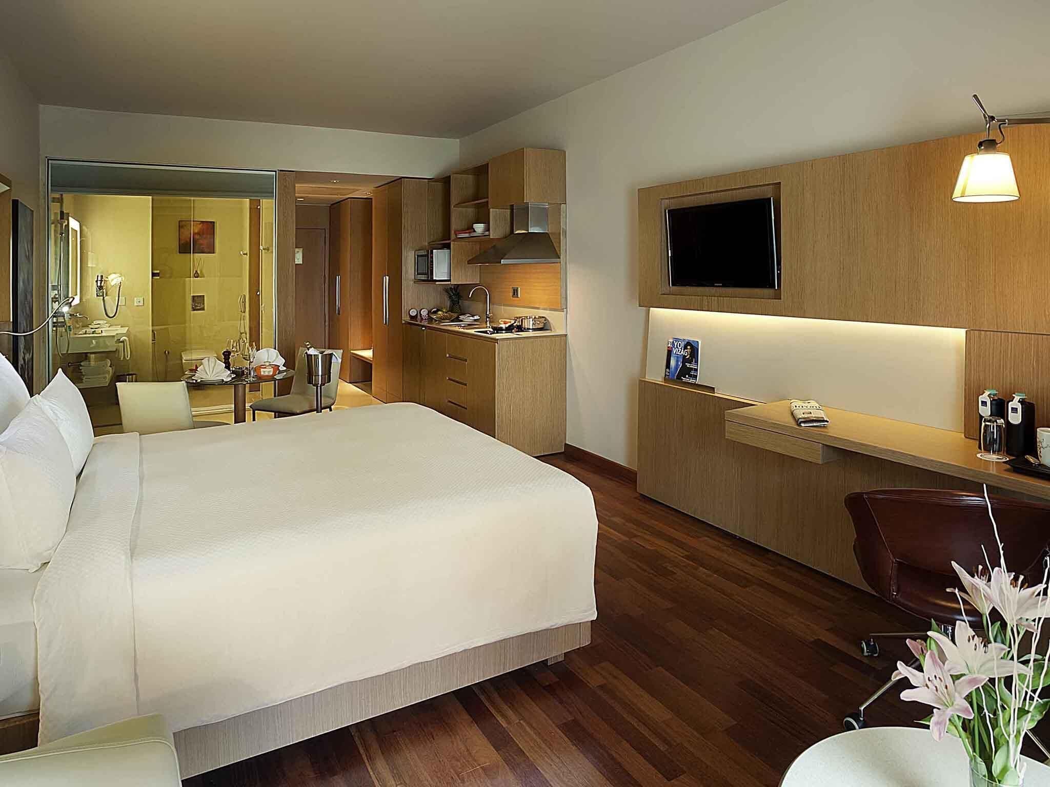 Ein Hotelzimmer mit Bett, Schreibtisch, Fernseher, Spiegel und Bad.