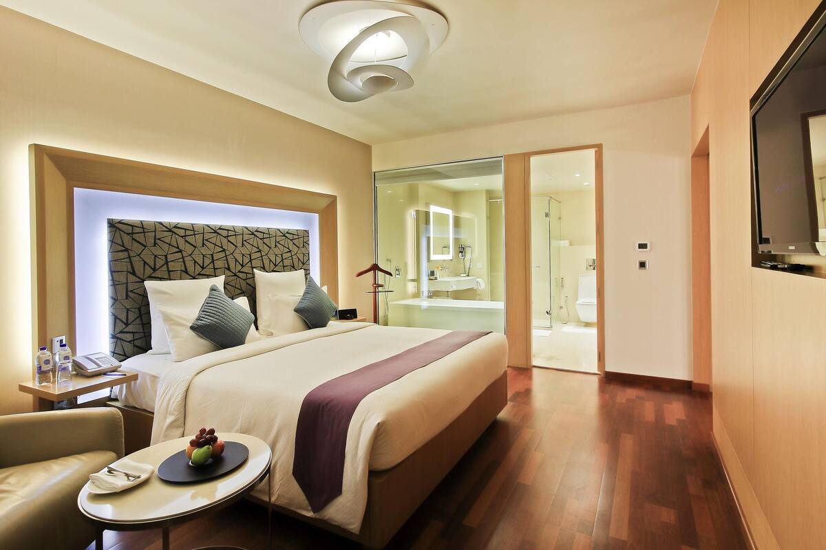 Une chambre d’hôtel avec un lit, une table de chevet, une chaise et un téléviseur.