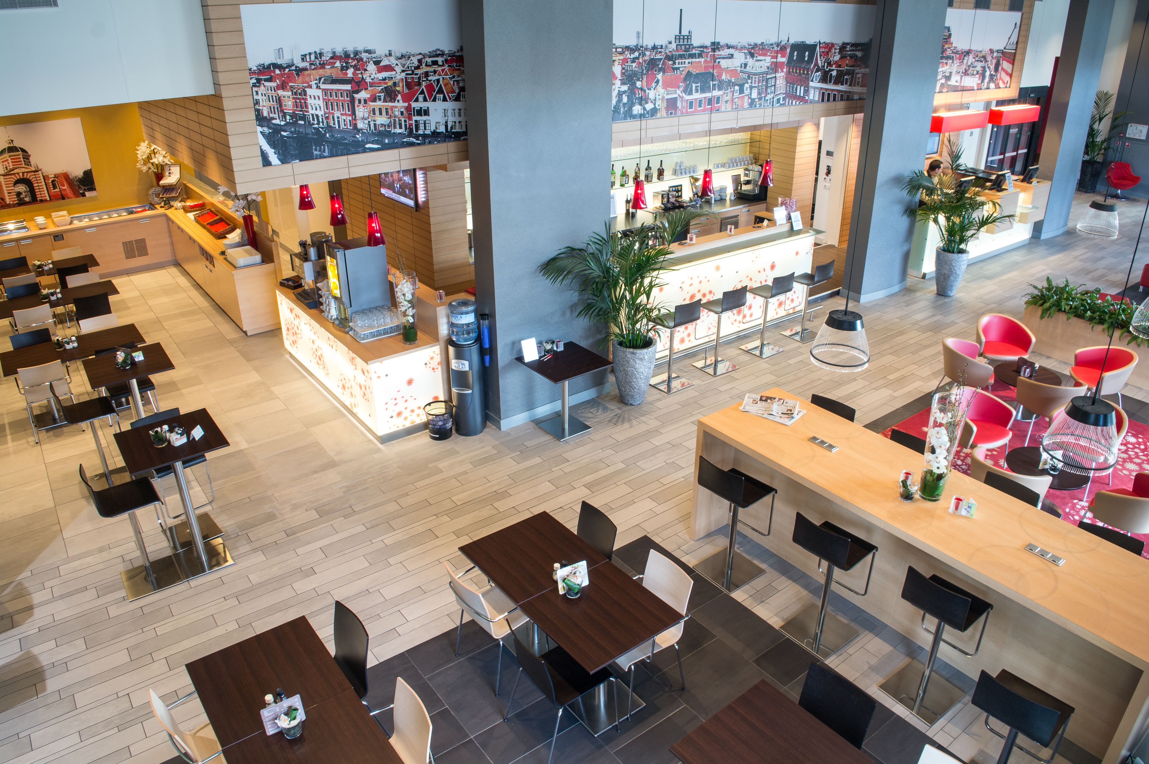 A modern hotel lobby with multiple dining areas, a bar, and a large cityscape view.