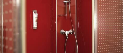 A red shower enclosure with a handheld showerhead and a handheld shower attachment.