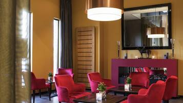 Un hall de hotel con sillas rojas, un panel de pared de madera, un espejo grande y una chimenea.