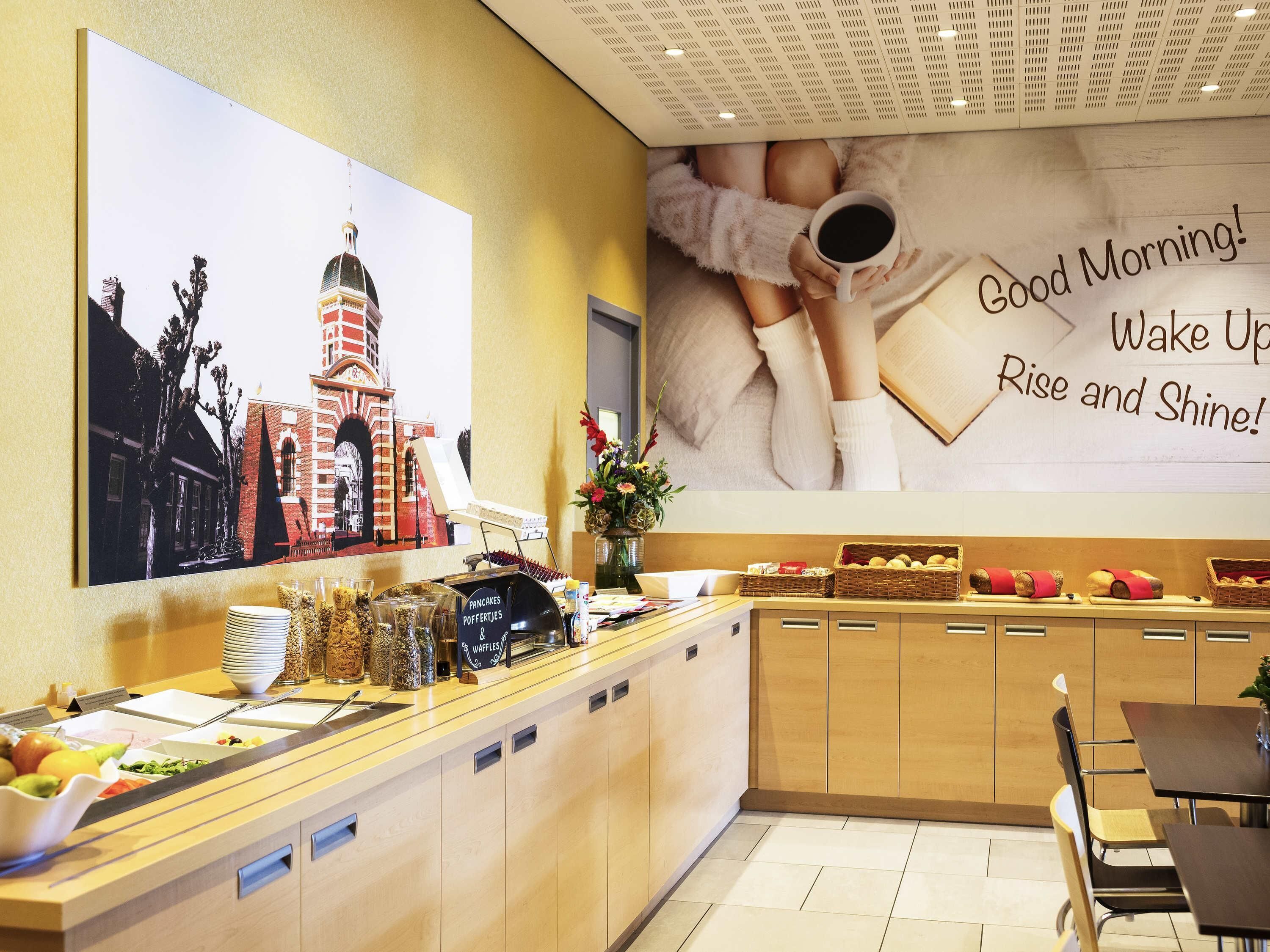 Zona de desayuno tipo buffet con diversas opciones de comida y un gran cartel inspirador en la pared.