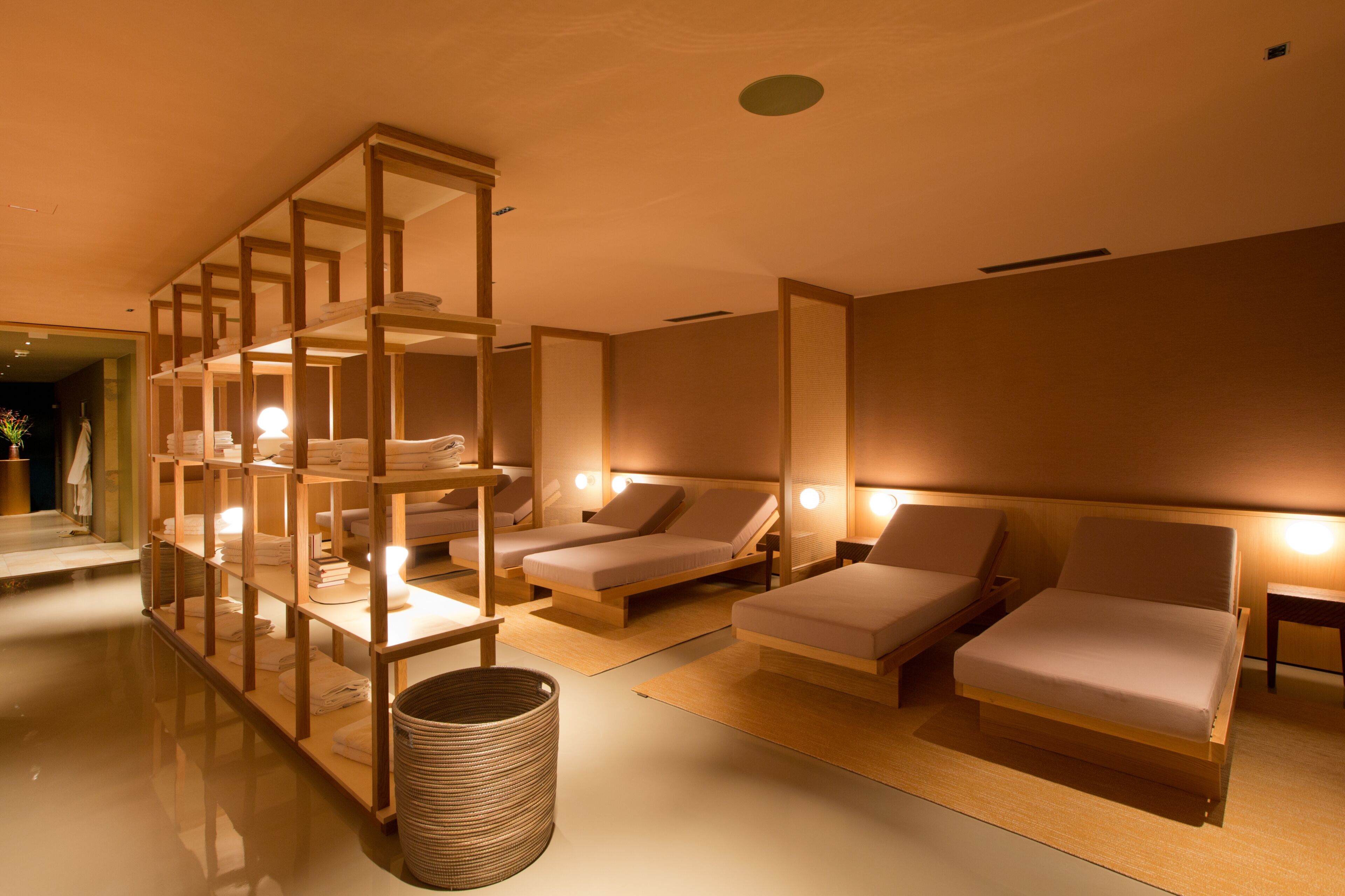 Ein Spa-Raum mit zwei Liegestühlen, einer Holzablage mit Handtüchern und einem gewebten Korb.