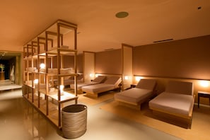 A spa room with two lounge chairs, a wooden shelf with towels, and a woven basket. - Sonnenburg (Lech am Arlberg)