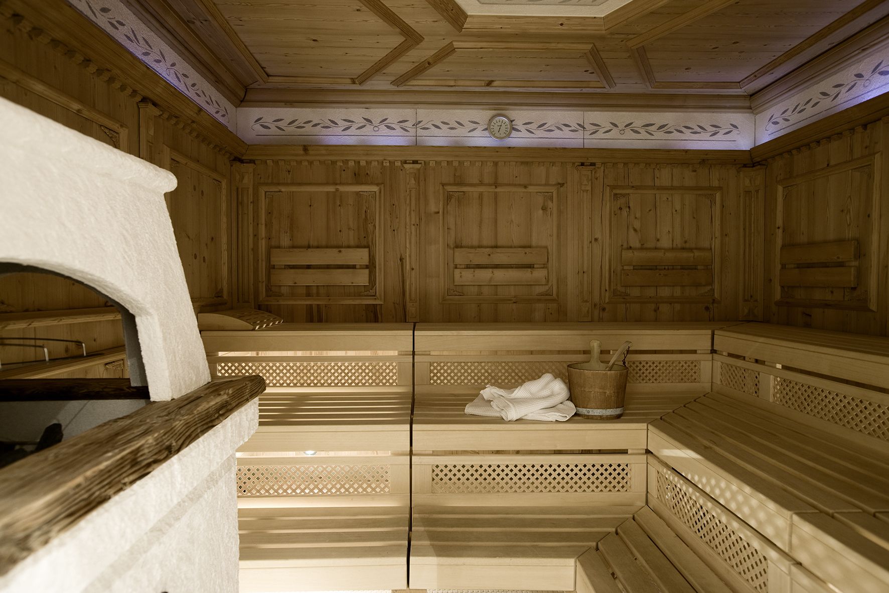 Una sauna con bancos de madera y un cubo de madera con un cepillo.