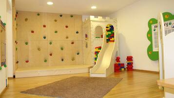 A playroom with a climbing wall, a slide, and colorful play structures.