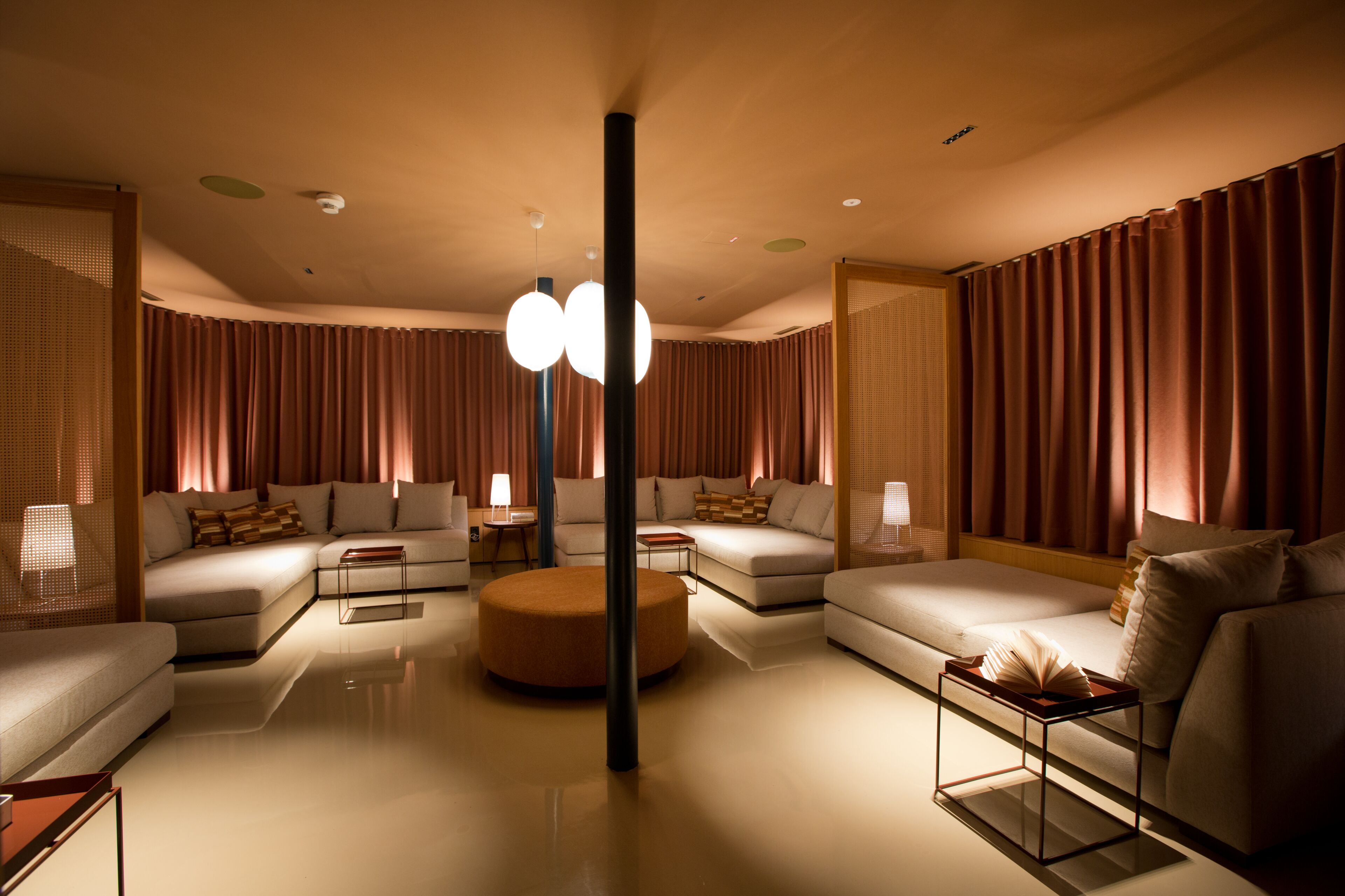 A modern living room with a sectional sofa, a round ottoman, and a glass coffee table.