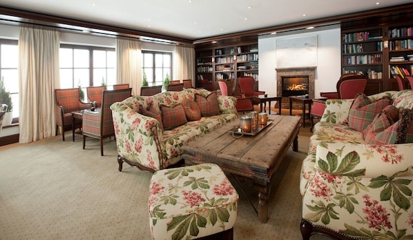 A cozy living room with a floral sofa set, a wooden coffee table, and a fireplace.