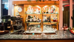 A bar area with shelves of liquor bottles, a coffee machine, and a clock on the wall. - Hotel Angelini (Rimini)